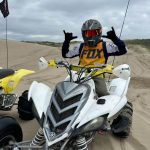 ATV rider showing a hand gesture in the sand dunes