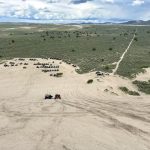 Looking down a sand dune towards some ATVs